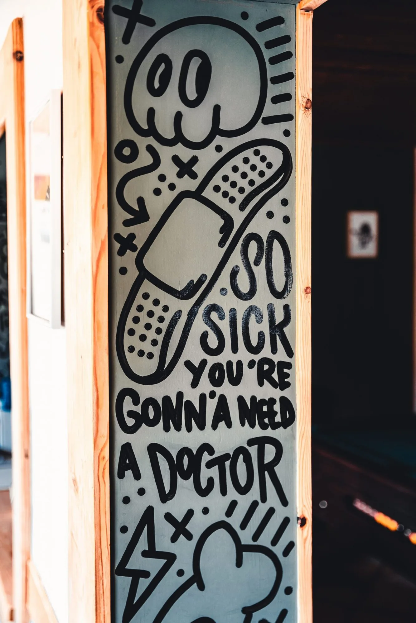 Black marker artwork on a panel: a skull and a plaster with the words "So sick you're gonna need a doctor"