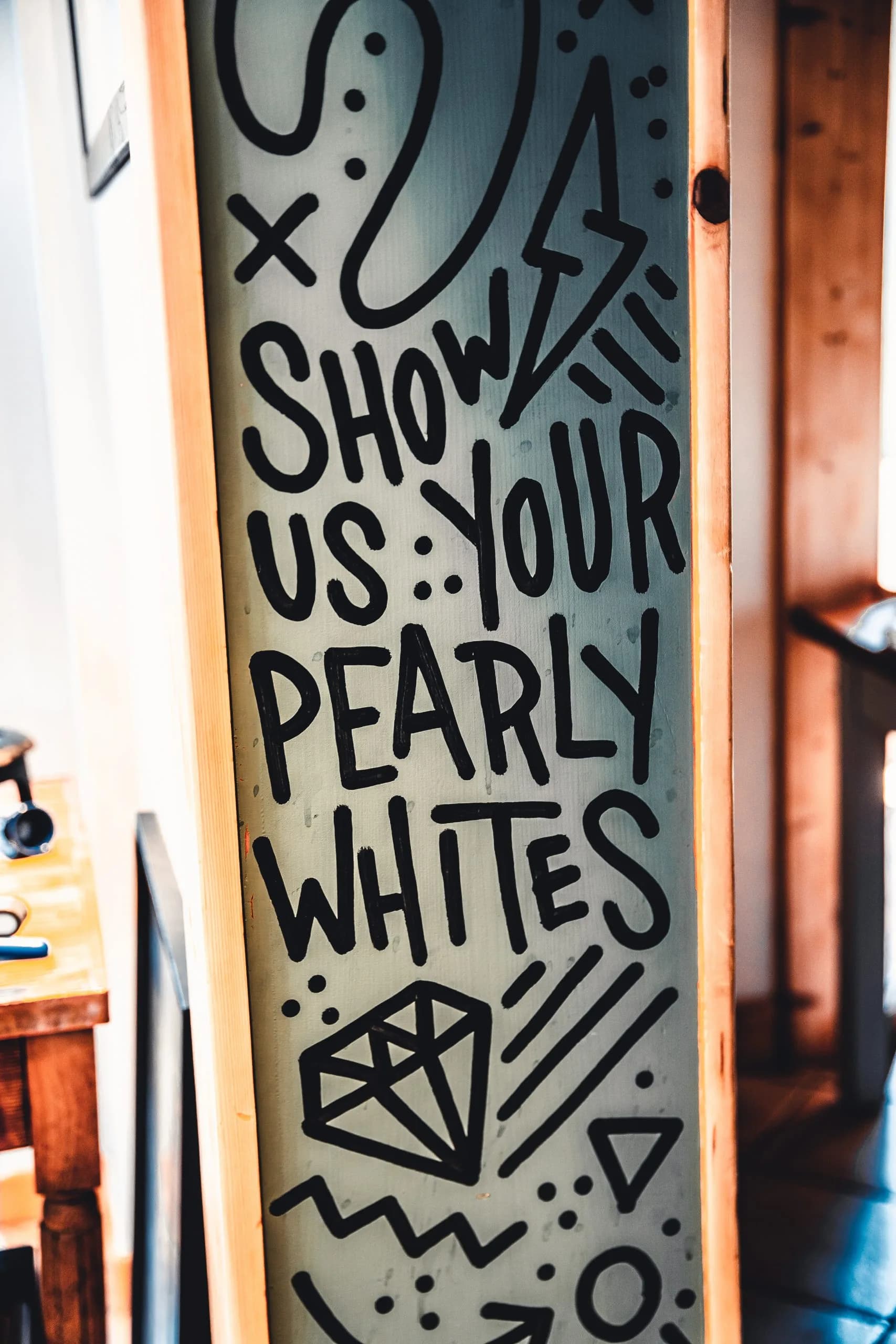 Hand-lettered wall art reading Show us your pearly whites, with a diamond drawing