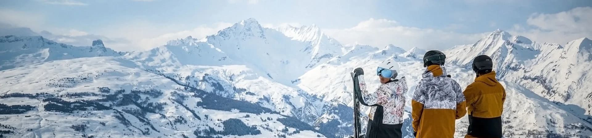 Skiërs en snowboarders kijken op een heldere dag uit over besneeuwde bergtoppen