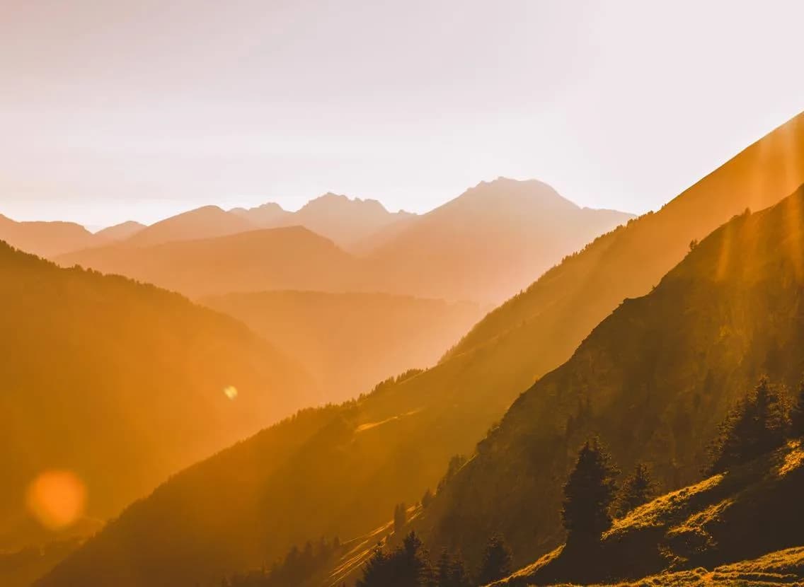 Layered mountain ridges glowing in hazy golden sunlight