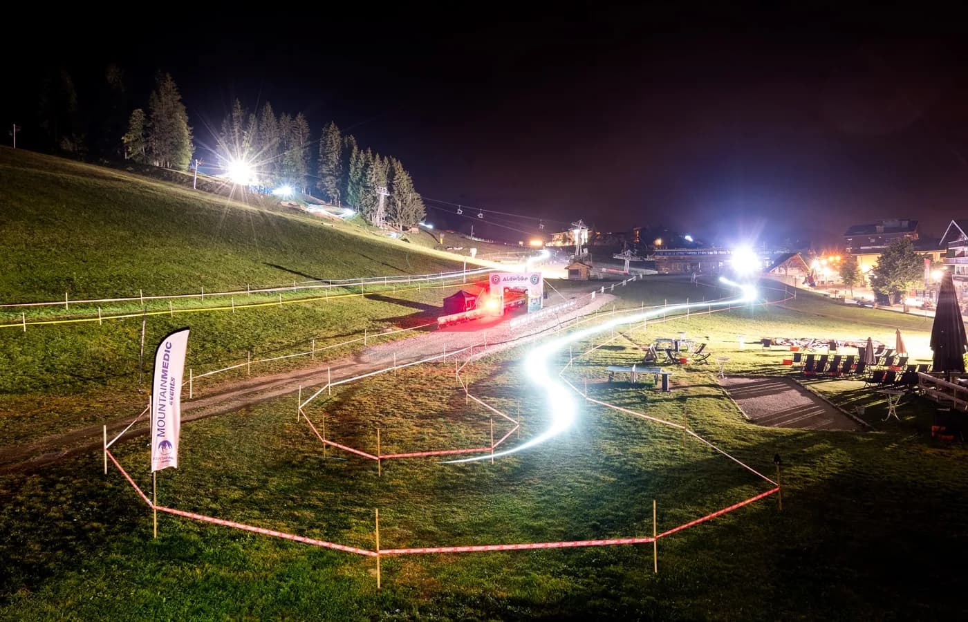 Verlicht fietsparcours bij nacht op een grashelling met een lichtspoor van een renner