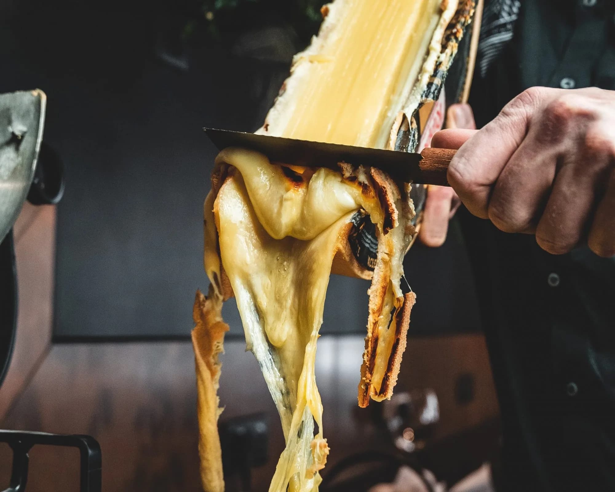 Melted cheese being scraped from a heated wheel.