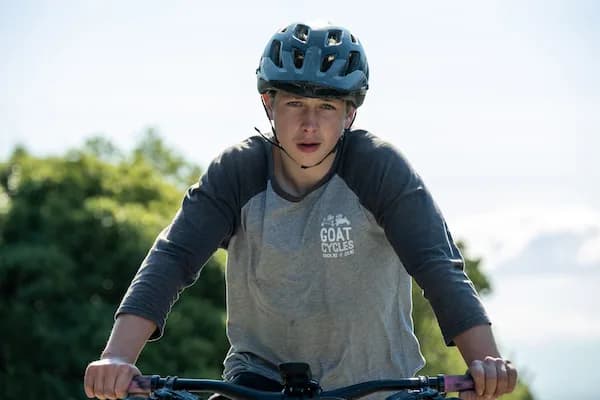 Radfahrer mit Helm und Goat-Cycles-Shirt, die Hände am Lenker