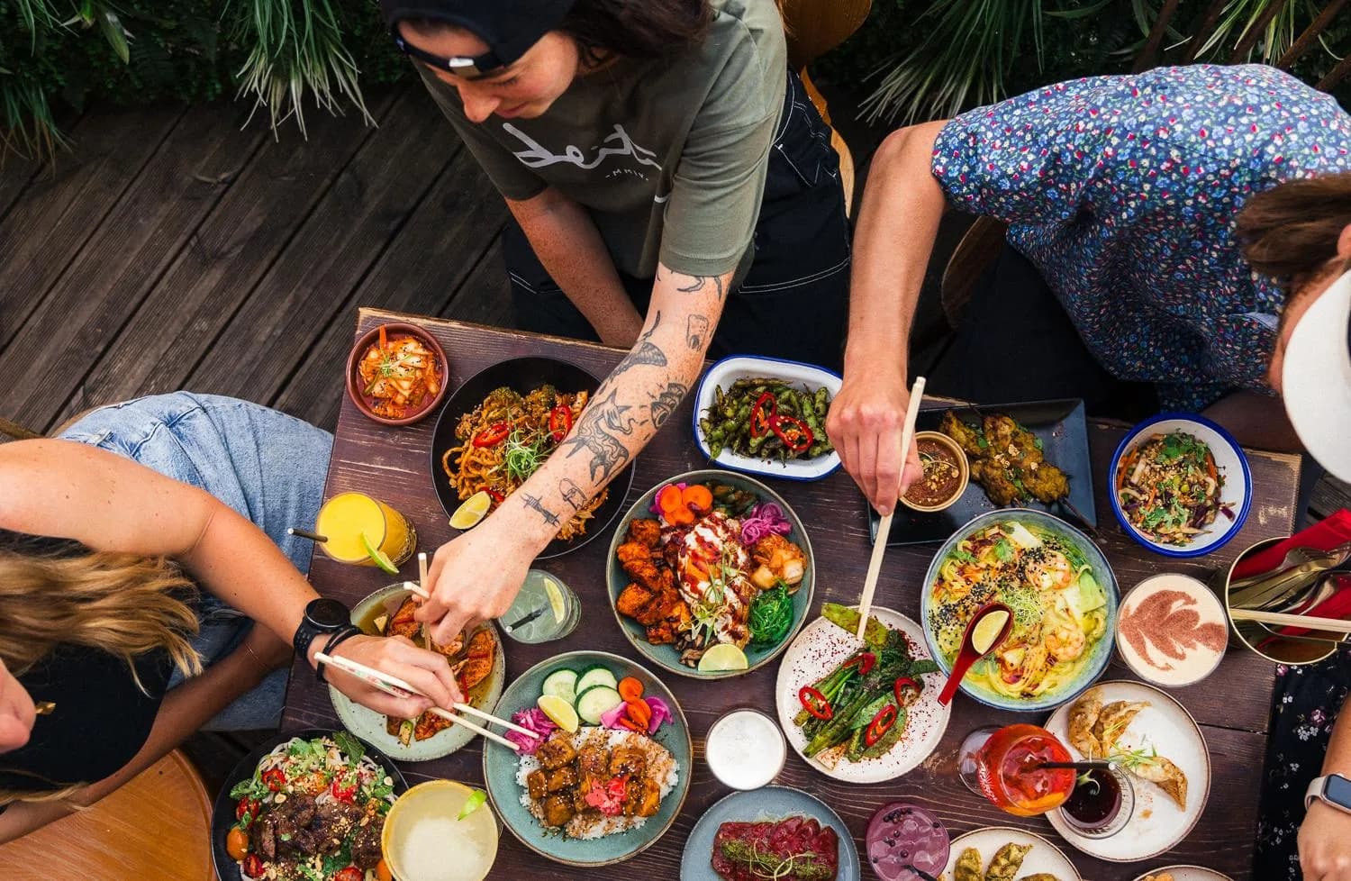 An overhead view of friends sharing colourful dishes and drinks