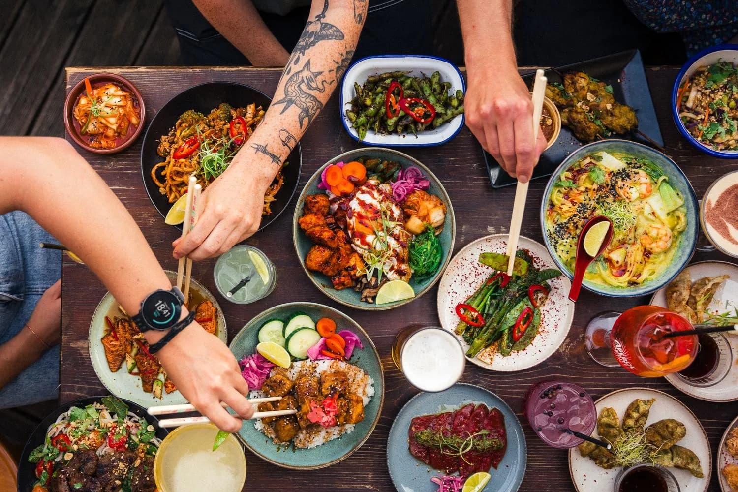 Diners reaching across the table to share bowls and plates