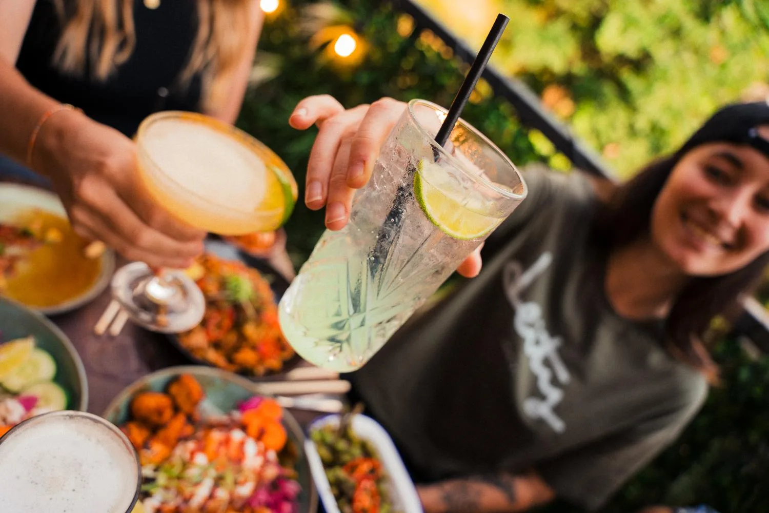 Friends raising their drinks above a table of sharing plates
