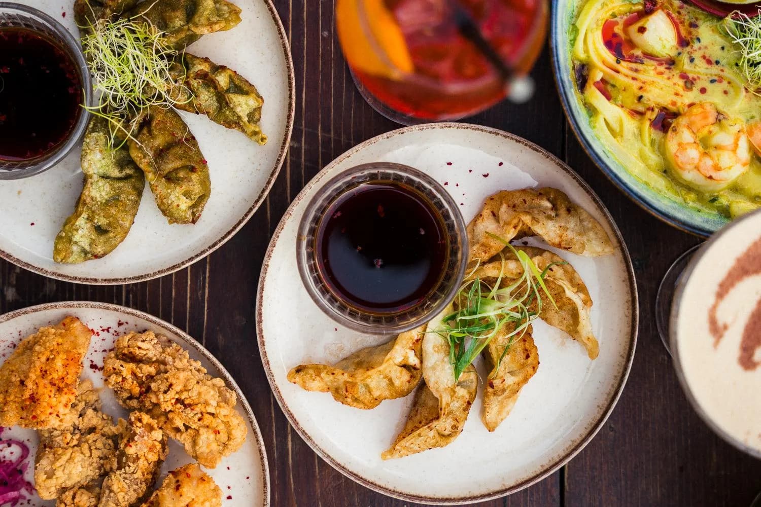Dumplings und Dip zwischen vielen kleinen Tellern zum Teilen
