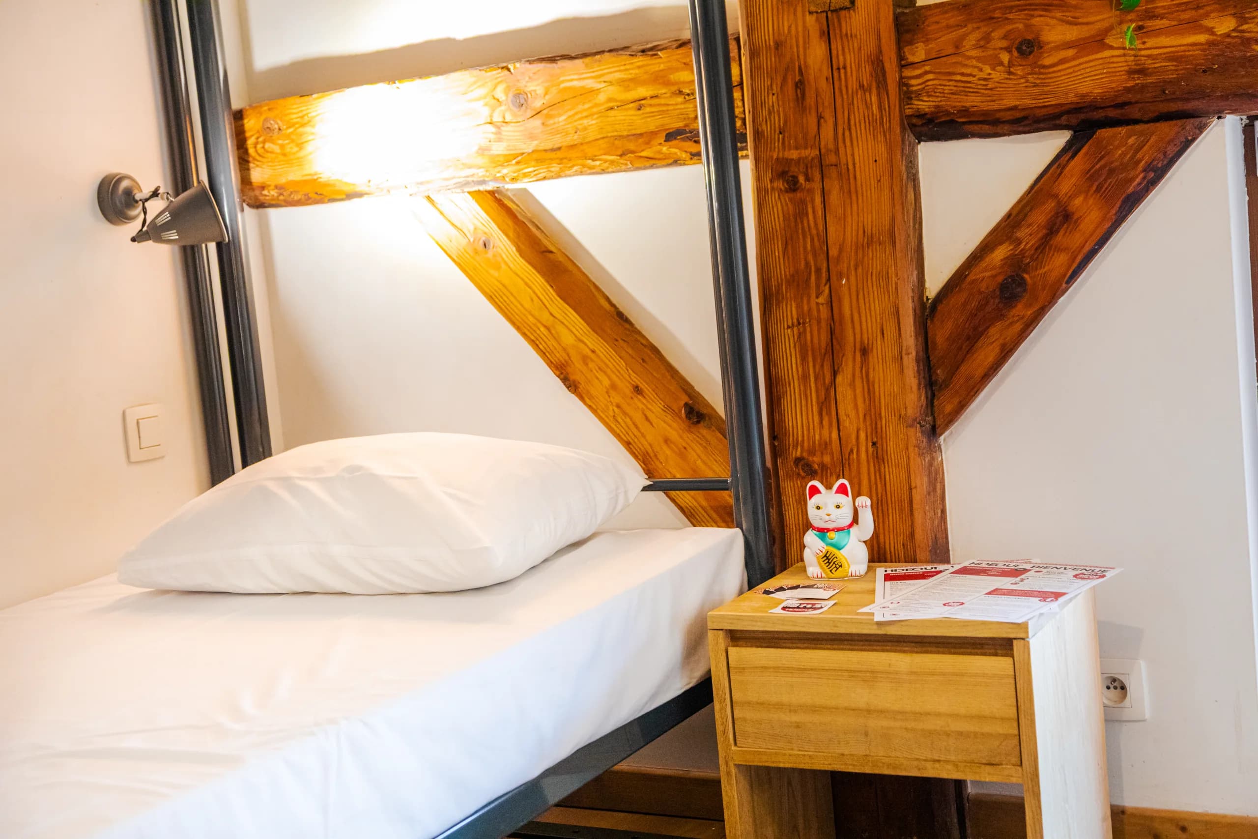 Bett in einem Zimmer im Hideout neben dem originalen Holzfachwerk des Gebäudes