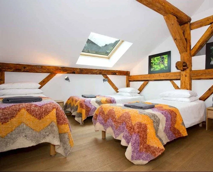 Dreibettzimmer mit drei Betten, Holzbalken und Dachfenstern
